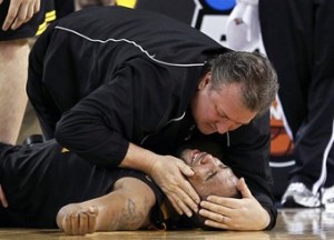 West Virginia's Butler is consoled by coach Huggins after injuring his knee against Duke in Indianapolis